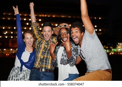 Multi-ethnic Millenial Group Of Friends Posing For A Photo Using Flash Outdoors At Night Time