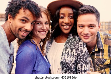 Multi-ethnic Millenial Group Of Friends Taking A Selfie Photo With Mobile Phone On Rooftop Terrasse At Sunset