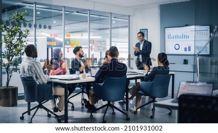 Multi-Ethnic Office Conference Room. Indian CEO does Presentation for Diverse Young Entrepreneurs, Talking, Using TV with Infographics, Statistics, Graphs. Businesspeople Invest in e-Commerce Startup