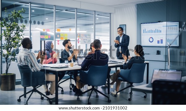 Multi-Ethnic Office Conference Room. Indian CEO\
does Presentation for Diverse Young Entrepreneurs, Talking, Using\
TV with Infographics, Statistics, Graphs. Businesspeople Invest in\
e-Commerce Startup