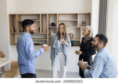 Multiethnic office friends enjoying work break in co-working space, drinking hot coffee together, discussing job, career, projects over cup of tea, enjoying offline communication - Powered by Shutterstock