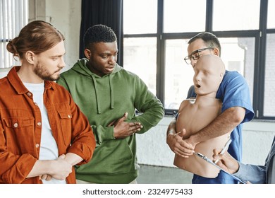 multiethnic participants of medical seminar looking at healthcare worker with CPR manikin showing first aid techniques in case of choking, emergency situations preparedness concept - Powered by Shutterstock - Get 15% off with code: PIKWIZARD15