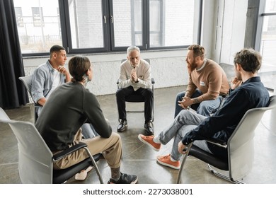 Multiethnic people with alcohol addiction sitting in circle in rehab center