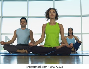 Multiethnic people sitting in lotus position at gym
