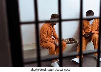 multiethnic prisoners playing chess behind prison bars - Powered by Shutterstock