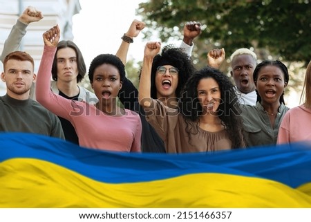 Multiethnic protestors striking against war in Ukraine on the street, blue and yellow flag. International group of young people making riot next to government building, collage Foto stock © 