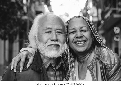 Multiethnic Senior Couple Looking At Camera Outdoor - Travel, Elderly People Concept - Focus On African Woman Face - Black And White Editing