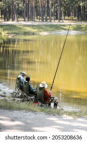 Multiethnic Senior Friends With Fishing Rod Sitting Near Lake In Park