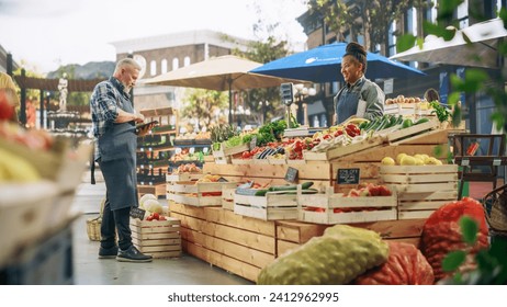 Multiethnic Small Business Owners Selling a Selection of Ecological Fruits and Vegetables at an Outdoors Farmers Market. Customers Walking Around the Square, Shopping for Fresh Organic Farm Produce - Powered by Shutterstock