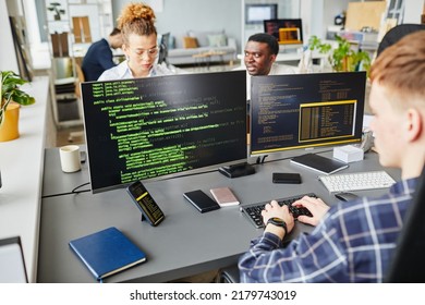 Multiethnic IT specialist working with program on monitors at office desk at IT company