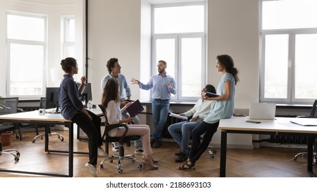 Multiethnic staff members gathered in coworking solve business, listen to male team leader during morning briefing in modern company office. Boss share information, corporate goals, tell about - Shutterstock ID 2188693103
