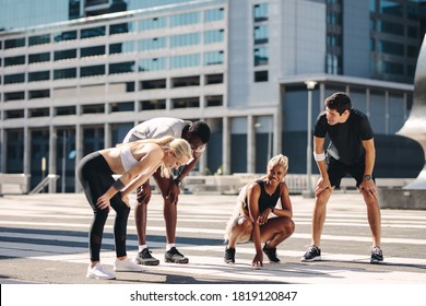 Multi-ethnic street runners taking a break after workout outdoors. Fitness group resting and smiling after running exercise in the city - Powered by Shutterstock