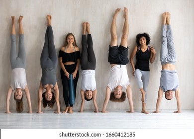 Multiethnic strong sportive people in sportswear posing standing near wall, diverse sportsmen sportswomen performing handstand smile look at camera, yoga work out finish, wellness, having fun concept - Powered by Shutterstock