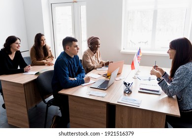 Multiethnic students and teacher study foreign languages together in class. Studing with laptop. Black handsome girl student study with white people together and look into camera