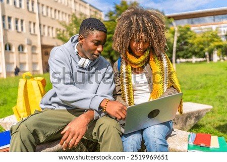 Multi-ethnic students using laptop sitting outside the university campus