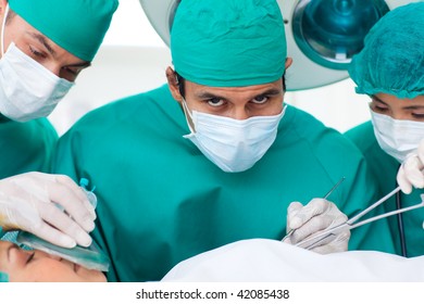 Multi-ethnic Surgeons Near Patient Lying On Operating Table In The Hospital. Healthcare Workers In The Coronavirus Covid19 Pandemic
