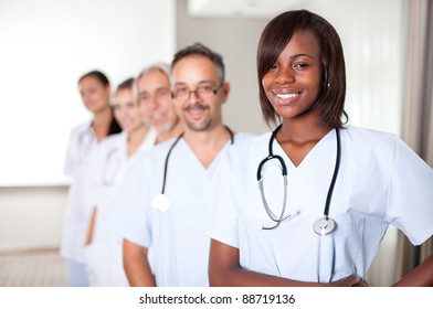 Multi-ethnic team of confident happy doctors standing in a row at the hospital