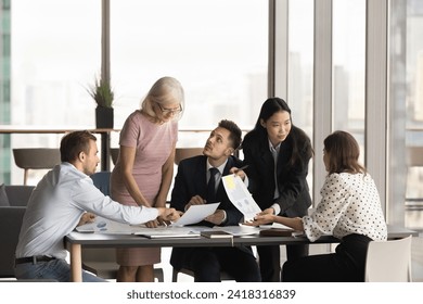 Multiethnic team of coworkers analyzing paper marketing reports at meeting table, brainstorming on sales result, reviewing documents together, discussing project strategy - Powered by Shutterstock