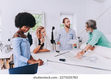 Multiethnic team of fashion designers working in a clothing start-up workshop - Multiracial group of stylists, tailor designers and dressmakers working on a new collection - Powered by Shutterstock