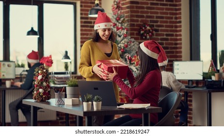 Multiethnic team of people giving presents during christmas festivity, celebrating winter holiday in startup office. Coworkers exchanging xmas gifts, seasonal festive decorations. - Powered by Shutterstock