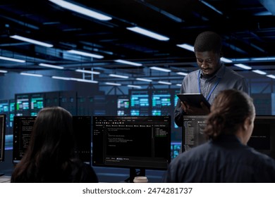 Multiethnic team in server room checking recovery plan and monitoring energy consumption. Diverse group of employees in data center location doing routine disk checks across components - Powered by Shutterstock - Get 15% off with code: PIKWIZARD15