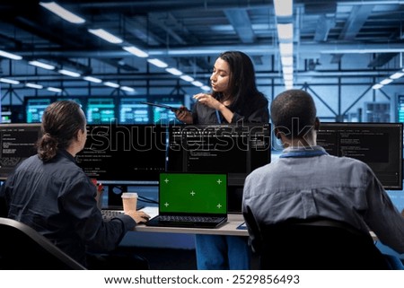 Multiethnic team in server room checking recovery plan and monitoring energy consumption using green screen laptop. Multiracial employees in data center doing disk checks using mockup notebook