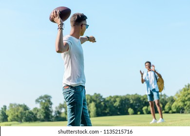 multiethnic teenage boys playing with rugby ball in park - Powered by Shutterstock