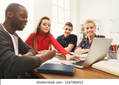 Multiethnic university students studying together. Young people working with tests and gadgets at wooden table. Education and technology concept, copy space