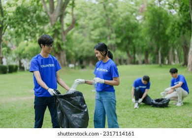 Multiethnic volunteers donate their time holding black garbage bags to collect plastic waste for recycling to reduce pollution in a public park - Powered by Shutterstock