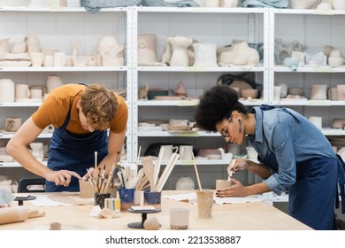 Multiethnic Woman And Man Shaping Clay Cups During Pottery Class