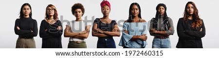 Multiethnic women standing together with arms crossed. Strong young women with diverse ethnicities.