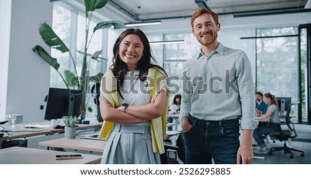Multi-ethnic workers giving high-five to each other after successful meeting or deal. Loudly smiling during conversation in office. Managers working at computers in background. Communication concept.