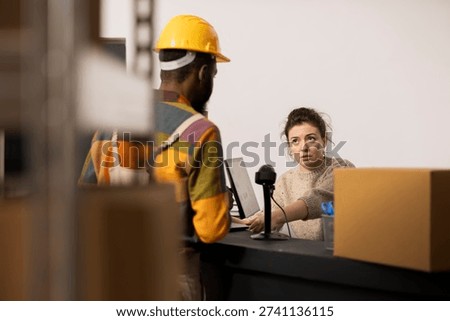 Multiethnic workers manage packaging and logistics in a small scale warehouse, preparing parcels for shipment service and verifying the inventory stock for retail e-business. Dispatch.