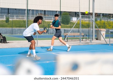 Multi-ethnic young sportive friends playing pickleball outdoors in a sunny day - Powered by Shutterstock