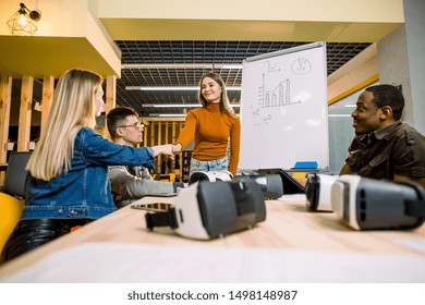 Multiethnical business people having team training exercise during seminar with VR glasses. Young girl in orange sweater presenting results of the project for coworkers - Powered by Shutterstock