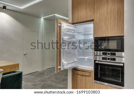 Multifunctional modern kitchen. Built-in appliances. Opened door of the new fridge Foto d'archivio © 