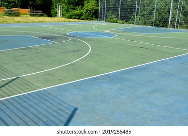 multifunctional outdoor playground for ball games at school. green artificial turf from a plastic carpet with lines. basketball hoops and soccer goals. around the grabbing high net and guardrails - Powered by Shutterstock