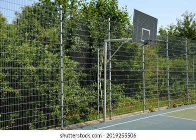 multifunctional outdoor playground for ball games at school. green artificial turf from a plastic carpet with lines. basketball hoops and soccer goals. around the grabbing high net and guardrails - Powered by Shutterstock