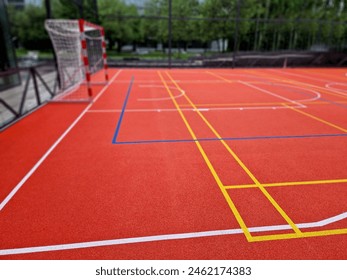 multifunctional outdoor playground for ball games at school. green artificial turf from a plastic carpet with lines. basketball hoops and soccer goals. around the grabbing high net and guardrails  - Powered by Shutterstock