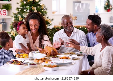 Multi-Generation Family Celebrating Christmas At Home Eating Meal And Making Toast With Water - Powered by Shutterstock