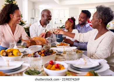 Multi-Generation Family Celebrating Christmas At Home Eating Meal And Making Toast With Wine - Powered by Shutterstock