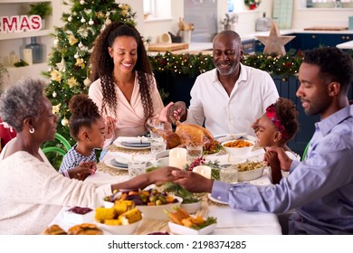 Multi-Generation Family Celebrating Christmas At Home Saying Prayer Before Eating Meal Together