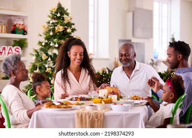 Multi-Generation Family Celebrating Christmas At Home Saying Prayer Before Eating Meal Together - Powered by Shutterstock