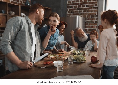 Multigeneration Family Cooking Dinner Together In Kitchen At Home