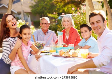 Multi-Generation Family Enjoying Outdoor Meal In Garden