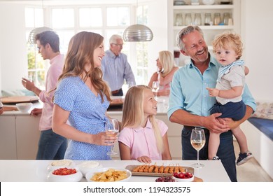 Multi-Generation Family And Friends Gathering In Kitchen For Celebration Party