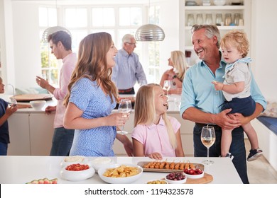 Multi-Generation Family And Friends Gathering In Kitchen For Celebration Party