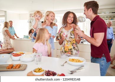 Multi-Generation Family And Friends Gathering In Kitchen For Celebration Party