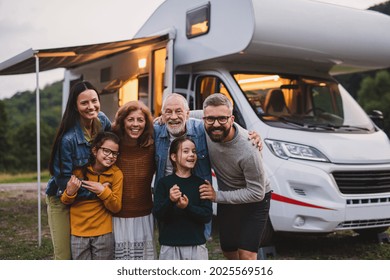 Multi-generation Family Looking At Camera Outdoors At Dusk, Caravan Holiday Trip.