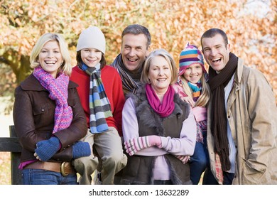 Multi-generation Family On Autumn Walk Sitting On Fence